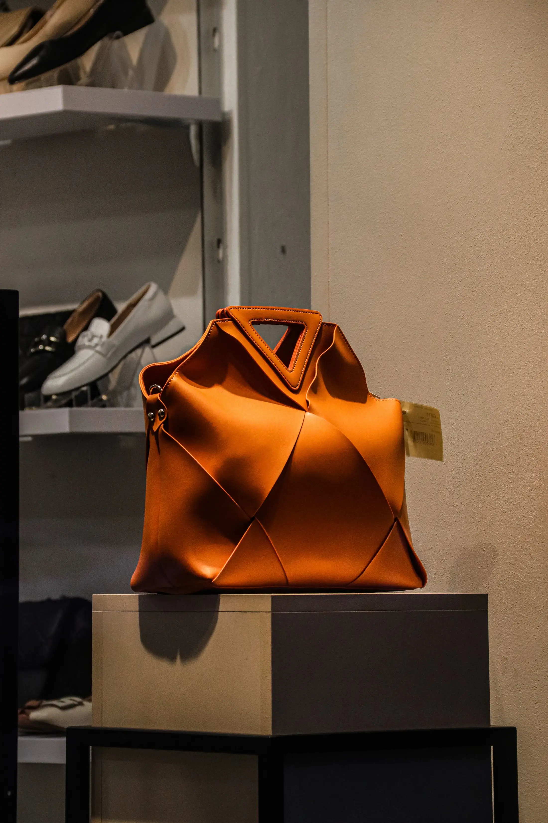 An orange leather handbag on display at a boutique